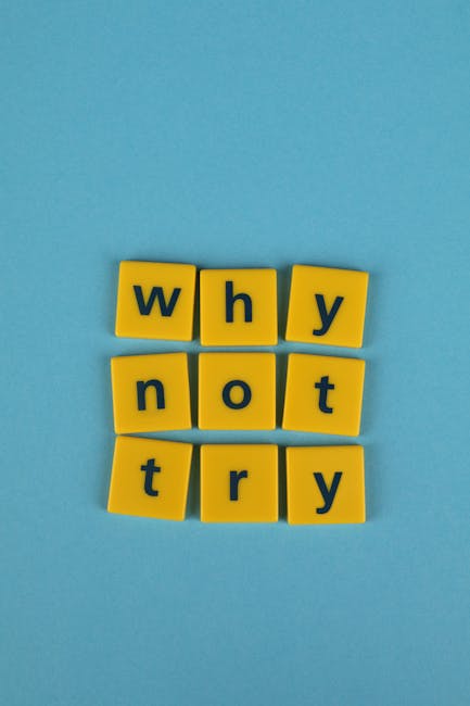 The image shows six yellow square tiles with black lowercase letters arranged on a light blue background. The tiles spell out the phrase 'why not try,' with three tiles on the top row and three on the bottom. The tiles are evenly spaced and aligned, creating a neat, simple visual message. This arrangement may symbolize encouragement or motivation, often related to decision-making or trying new activities, such as home relocation or moving services offered by Man with Van Sanderstead. The clean background and clear lettering ensure accessibility for visually impaired viewers and support SEO relevance in the context of moving and packing services.